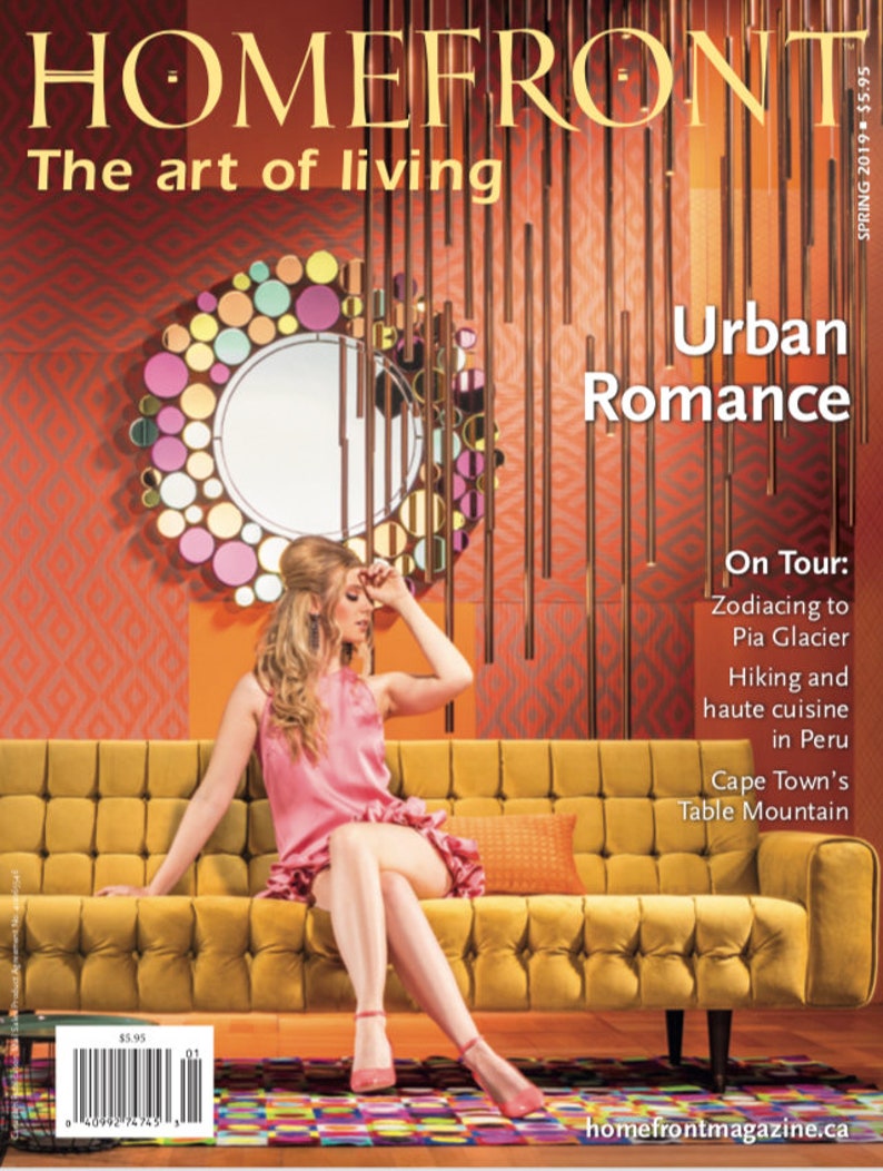 May include: A magazine cover featuring a woman sitting on a yellow tufted sofa. The cover features the text "HOMEFRONT The art of living" and "Urban Romance". The magazine cover also features the text "On Tour: Zodiacing to Pia Glacier Hiking and haute cuisine in Peru Cape Town's Table Mountain".
