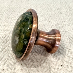 The green kitchen hardware knob has an oil rubbed bronze finish.