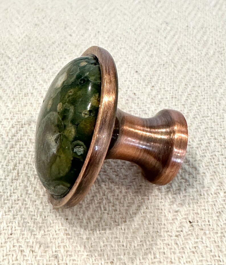 The green kitchen hardware knob has an oil rubbed bronze finish.