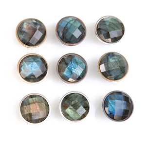 Pode incluir: Nove botões redondos, iridescentes, com aparência de gema, com uma borda de metal prateado ou dourado. Os botões têm uma gama de cores azul escuro, verde e cinza.
