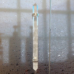 Può includere: Una maniglia per porta in cristallo trasparente con una fascia di metallo argentato in alto e in basso. La maniglia ha la forma di un cristallo appuntito.