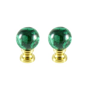 May include: Two green malachite finials with gold bases. The finials are round and have a swirling pattern.