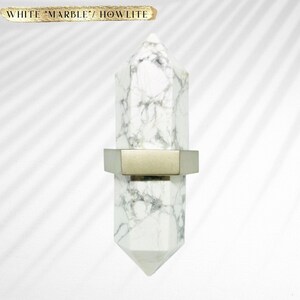 May include: White Howlite crystal cabinet knob with a silver hexagonal base. "WHITE "MARBLE" HOWLITE" is written in gold lettering at the top of the image.