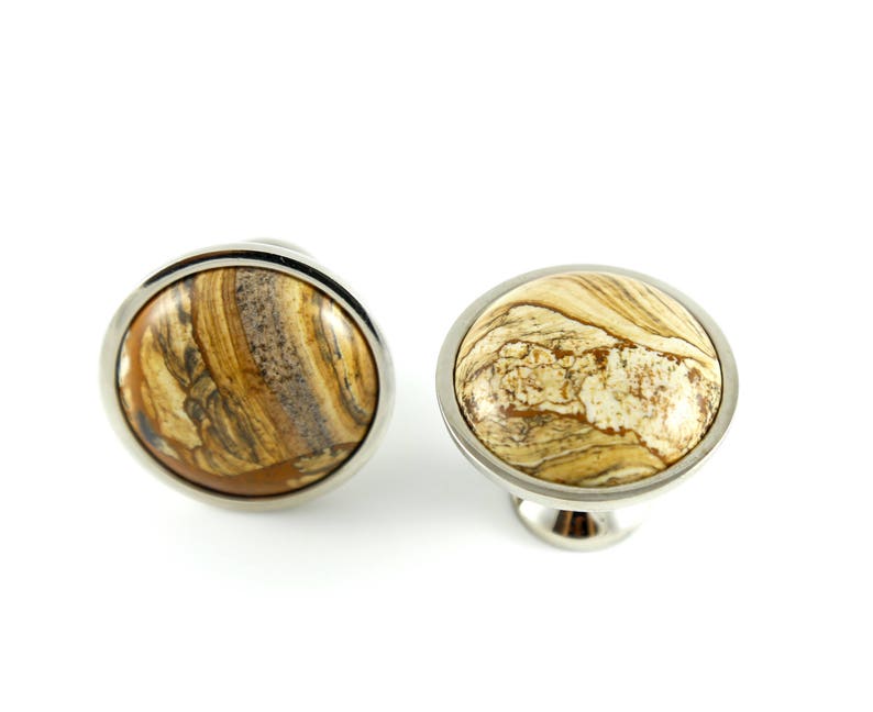 May include: Two round cabinet knobs with a silver metal base and a brown and white marbled stone top.