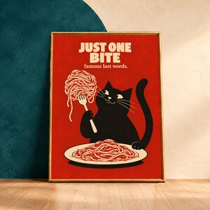 May include: A rectangular framed wall art print with a red background featuring a black cat holding a fork with a twirl of spaghetti. Below the cat is a plate of spaghetti. The text reads JUST ONE BITE famous last words.