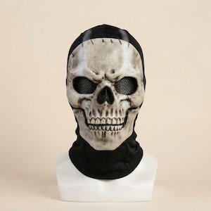 May include: A full-head mask featuring a realistic, weathered off-white skull face with deep-set eye sockets covered by black metal mesh. The skull is attached to a black fabric hood that covers the neck and head, creating a seamless look.