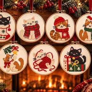 May include: Seven circular wooden embroidery hoops featuring cross-stitch designs of cats in holiday attire. The cats are depicted with red scarves, hats, stockings, yarn balls, and gift boxes, all suspended by red ribbons against a festive backdrop.