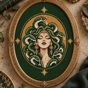May include: An oval cross-stitch embroidery featuring a central figure with closed eyes and hair composed of green snakes, set against a dark green background with gold accents, all encased in an ornate, metallic gold frame with a Greek key pattern.