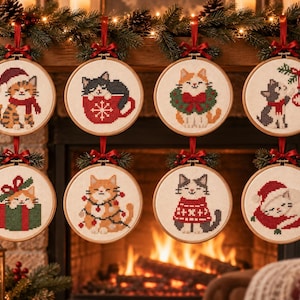 May include: Eight circular wooden embroidery hoops featuring cross-stitch cat designs with holiday themes. Each hoop is suspended by a red ribbon and decorated with a small sprig of greenery. The cats are depicted in various festive scenes.
