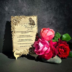 May include: A rectangular wooden wedding invitation plaque featuring a laser-engraved portrait of a couple, floral borders, and text detailing a marriage celebration on Saturday, 12 June 2027, at The Grand Willow Estate in Charleston, South Carolina.