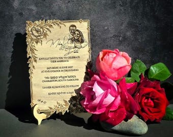 May include: A rectangular wooden wedding invitation plaque featuring a laser-engraved portrait of a couple, floral borders, and text detailing a marriage celebration on Saturday, 12 June 2027, at The Grand Willow Estate in Charleston, South Carolina.