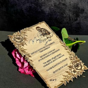 May include: A rectangular wooden wedding invitation with laser-engraved floral borders, a portrait of a couple, and text reading: Joyfully invite you to celebrate their marriage, Saturday, 12 June 2027, The Grand Willow Estate, Charleston, South Carolina.
