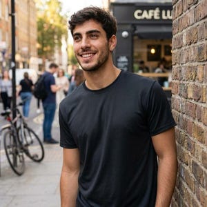 May include: A solid black short-sleeved crew neck t-shirt made of a smooth, lightweight fabric. The shirt features a standard fit with a simple, unadorned design, a rounded neckline, and hemmed sleeves, providing a clean and basic appearance.