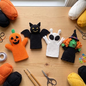 Pode incluir: Quatro marionetas de mão feitas em croché, incluindo uma abóbora com caule verde, um morcego preto com olhos amarelos, um fantasma branco com olhos ovais pretos e uma bruxa de rosto verde com cabelo laranja e chapéu preto.