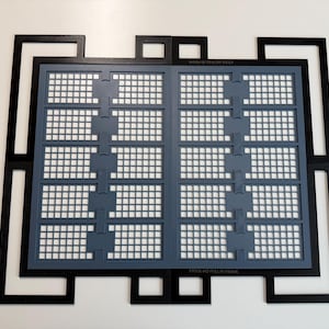 May include: A black rectangular frame with an intricate geometric border surrounds a gray grid insert. The gray insert features two vertical columns of five rectangular sections, each containing a small square grid pattern. The text XTOOL M2 FULL-RI FRAME is visible.
