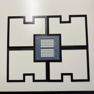 May include: A black xTool M1 small frame assembly consisting of four interlocking L-shaped pieces arranged in a square pattern. A central gray square component features a grid of small white squares and the text xTool M1-SMALL-FRAME.