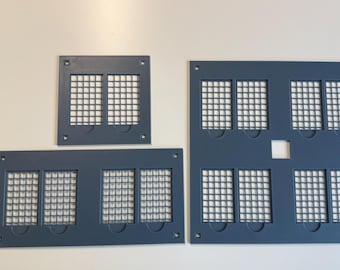 May include: Three dark gray rectangular panels featuring grid-patterned cutouts. The top left panel has two grid sections, the bottom left has four, and the large right panel contains eight grid sections with a small square hole in the center.