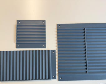 May include: Three dark gray rectangular ventilation grilles with horizontal slats and pre-drilled mounting holes in each corner. The set includes one large square grille, one smaller square grille, and one wide rectangular grille with vertical slats.