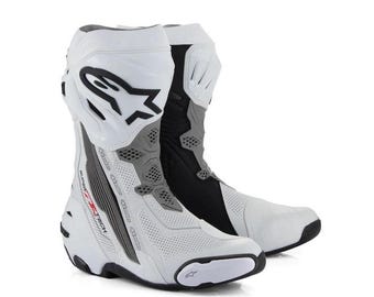 Puede incluir: Un par de botas de carreras para motocicleta en color blanco y negro con paneles de cuero perforado, una espinillera rígida con el logotipo de Alpinestars y el texto Supertech impreso en el lateral. Estas botas tienen un diseño elegante y protector.