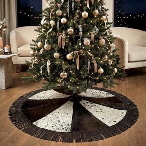 May include: A circular Christmas tree skirt featuring alternating panels of solid dark brown and white with black speckled cowhide-style patterns. The edge of the skirt is finished with a long, dark brown fringe trim that encircles the entire perimeter.