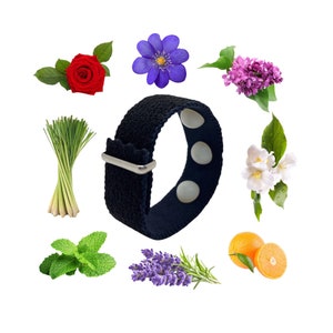 Peut inclure: Un bracelet en tissu noir avec quatre boutons magnétiques blancs. Le bracelet est entouré de diverses fleurs, herbes et agrumes, notamment de la lavande, de la menthe, de la citronnelle, de la rose, de l'orange et du jasmin.