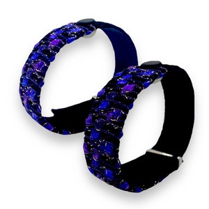 K&ouml;nnte beinhalten: Zwei Armb&auml;nder mit einem schwarzen Samtband und einem gewebten Design in Blau-, Lila- und Silbert&ouml;nen. Die Armb&auml;nder haben einen Verschluss und ein dekoratives Webmuster.