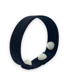 May include: Black fabric wristband with three white round buttons.