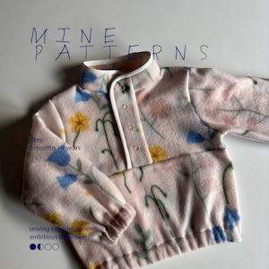 May include: A light pink fleece pullover with a floral print featuring blue and yellow flowers. The garment has a mock neck, a front placket with four snaps, and elasticized cuffs. Text reads: MINE PATTERNS, sizes: 0 months - 9 years, sewing experience level: ambitious beginner.