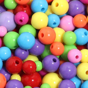May include: A collection of smooth, round, multi-colored plastic beads in various sizes. The assortment includes vibrant shades of red, orange, yellow, lime green, sky blue, purple, and pink, each featuring a central hole for threading.