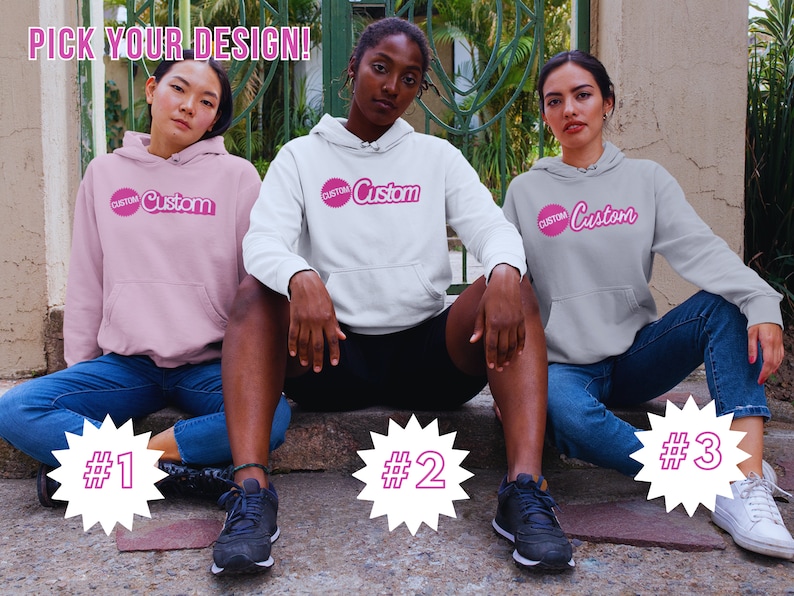 May include: Three people wearing hoodies with the word "Custom" in pink lettering on the front. The hoodies are pink, white, and gray. The people are sitting on a set of stairs with numbers 1, 2, and 3 behind them.