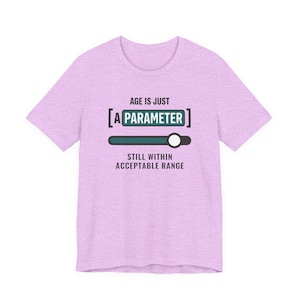 Peut inclure: Un t-shirt chiné violet clair avec le texte "AGE IS JUST [A PARAMETER]" en noir et bleu sarcelle, accompagné d'un graphique représentant une barre de curseur horizontale et le texte "STILL WITHIN ACCEPTABLE RANGE" imprimé en noir en dessous.