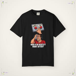 Könnte beinhalten: Ein schwarzes Kurzarm-T-Shirt mit einer Grafik einer Hand über zwei roten Knöpfen mit der Aufschrift USE MY BANKED RESET und WAIT FOR TIBO. Darunter wischt sich eine schwitzende Person die Stirn mit dem Text WHAT IF HE RESETS IT RIGHT AFTER?