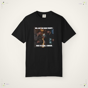 Peut inclure: Un t-shirt noir à manches courtes avec une impression graphique représentant deux personnes dans un décor sombre et le texte blanc "BRO, JUST ONE MORE PROMPT. THEN I'M DONE. I SWEAR.". Le t-shirt a un col rond et une coupe standard.