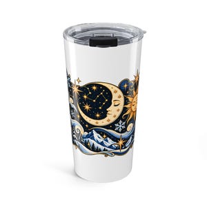 May include: A white cylindrical tumbler with a clear plastic lid featuring a graphic print of a crescent moon with a face, a sun, stars, snowflakes, and snow-covered mountains in shades of blue, gold, and white against a dark background.