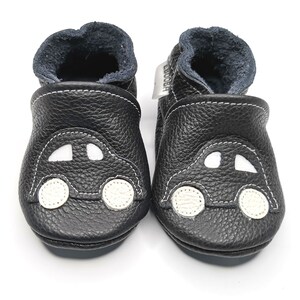 May include: Black leather baby shoes with a white car design. The shoes have a soft, flexible sole and are perfect for crawling and walking.