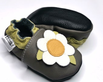 Può includere: Scarpe da bambino in pelle grigia con un'applicazione a fiore verde e bianco. Le scarpe hanno un'etichetta gialla con il testo "Ebooba" su di esse.