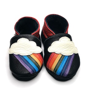 May include: Black leather baby shoes with a rainbow and cloud design. The shoes have a white cloud with a rainbow coming out of it.