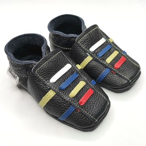 May include: A pair of black leather baby shoes with colorful stripes. The shoes have a label that says "Ebooba".