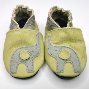 K&ouml;nnte beinhalten: Ein Paar Babyschuhe in hellgr&uuml;ner Farbe mit einem grauen Elefanten-Design. Die Schuhe sind aus weichem Leder gefertigt und bieten einen bequemen Sitz.