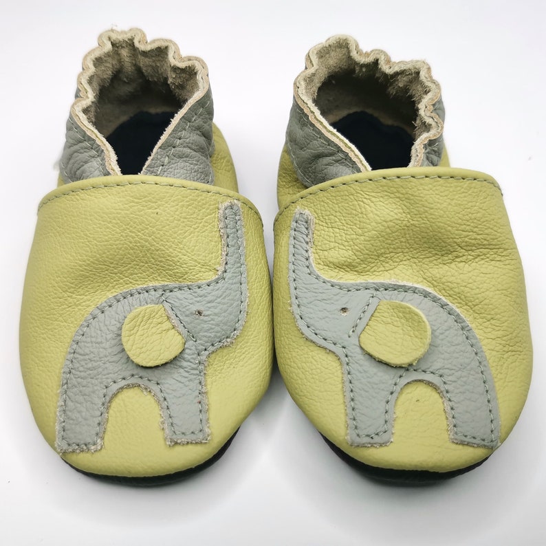 K&ouml;nnte beinhalten: Ein Paar Babyschuhe in hellgr&uuml;ner Farbe mit einem grauen Elefanten-Design. Die Schuhe sind aus weichem Leder gefertigt und bieten einen bequemen Sitz.