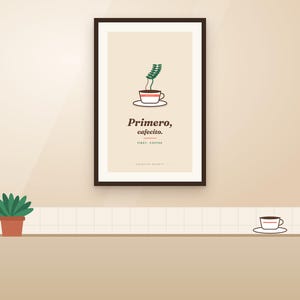 Könnte beinhalten: Ein gerahmter Wanddruck mit einer Grafik einer Kaffeetasse mit Dampf, dem Text "Primero, cafecito." und "FIRST, COFFEE." in dunkelbrauner Schrift, platziert über einer kleinen grünen Topfpflanze und einer einzelnen Kaffeetasse.