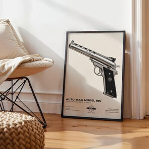 May include: A framed wall art print featuring a detailed illustration of an Auto Mag Model 180 classic magnum pistol. The print includes technical text specifications and the Auto Mag logo on a light cream background in a black frame.