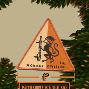 May include: A 4-inch orange and white triangular patch with a black monkey holding a rifle. The patch reads "Monkey Division T.M."