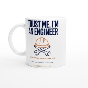 Könnte beinhalten: Ein weißer Keramikbecher mit dem dunkelblauen Text TRUST ME, I'M AN ENGINEER über einer Grafik eines orangefarbenen Schutzhelms, der mit zwei dunkelblauen Schraubenschlüsseln gekreuzt ist. Der Text enthält SOLVING PROBLEMS, ONE CALCULATION AT A TIME.
