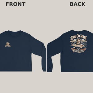 May include: A navy blue long-sleeve shirt featuring a small graphic on the front chest and a large graphic on the back. The back design shows a dog in an airplane with the text DOG CO-PILOT and BEST SEAT BUDDY. The front has a smaller version.