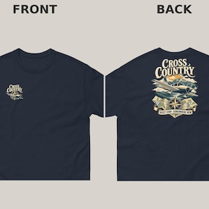 May include: A navy blue t-shirt featuring a small graphic on the front left chest and a large graphic on the back. Both prints show a light aircraft, a compass rose, and the text Cross Country. The back graphic adds the text Next Stop: Somewhere New.