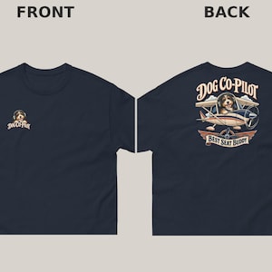 May include: A navy blue t-shirt featuring a small graphic on the front left chest of a dog wearing headphones with the text DOG CO-PILOT. The back displays a larger graphic of a dog in a small aeroplane with the text DOG CO-PILOT BEST SEAT BUDDY.