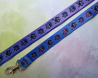 May include: Two purple and blue lanyards with a repeating pattern of small cartoon creatures. The lanyards have a silver metal clip.