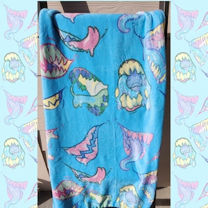 May include: A blue fleece blanket with a colorful, abstract pattern of dripping teeth. The pattern is repeated throughout the blanket.
