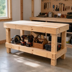 May include: A rectangular light-colored wooden workbench with a thick top and a lower storage shelf. The shelf holds a circular saw, two cordless power drills, a wooden tool tote, and a black plastic storage case with red latches.